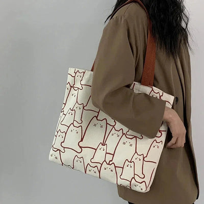 Person holding a tote bag with cat pattern against a plain background
