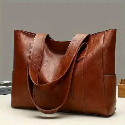 Brown leather tote bag on a light gray background