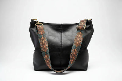 Black leather handbag with decorative brown straps on a white background