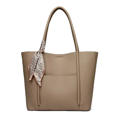 Beige handbag with a patterned scarf draped over the handle on a white background