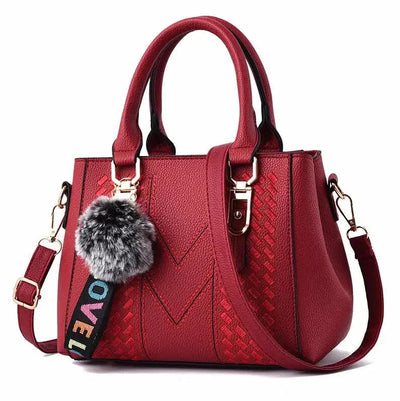 Red handbag with a fur pom-pom and colorful strap on a white background